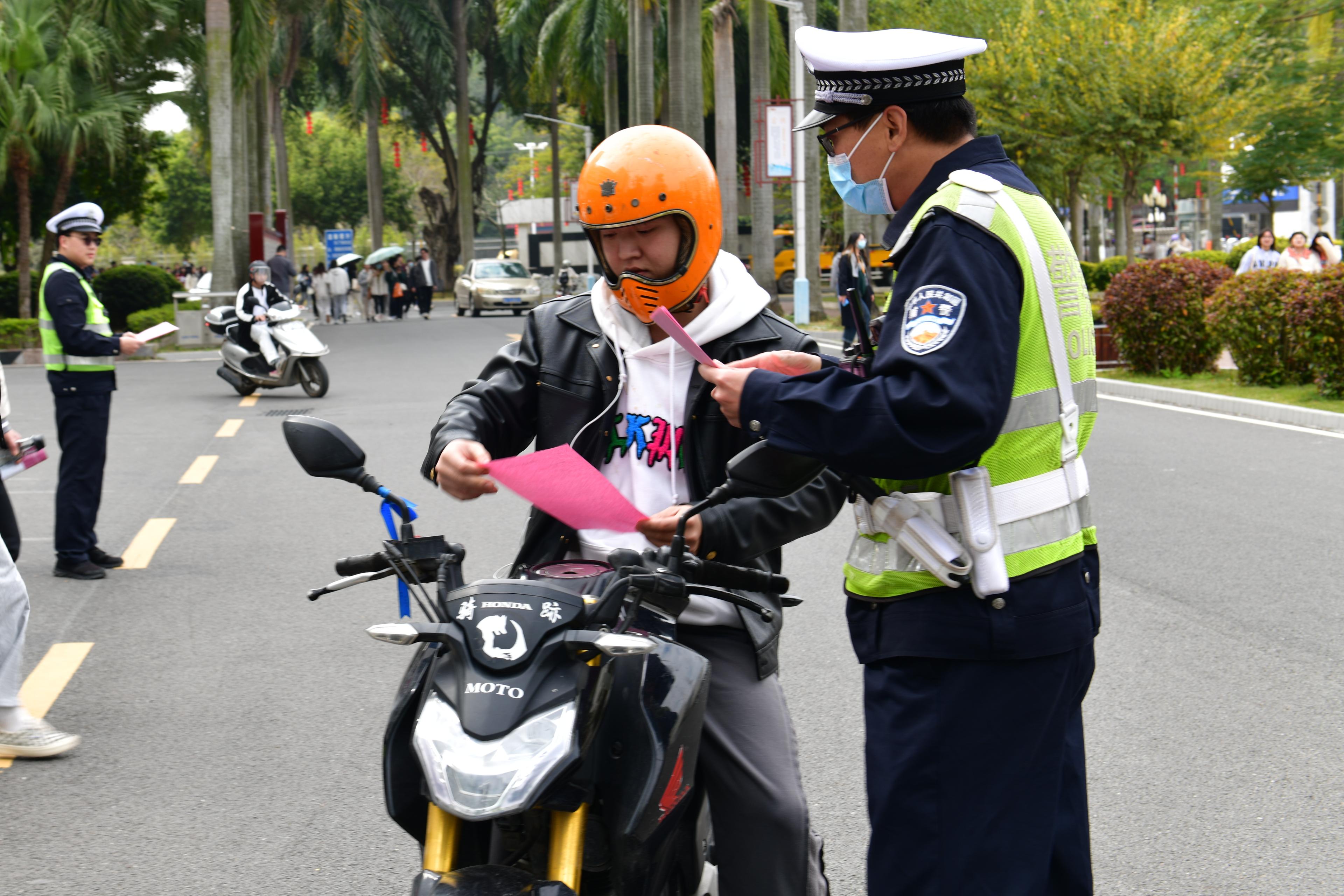 警官在學校東校區開展交通督導執法,一邊為路人散發交通安全宣傳資料